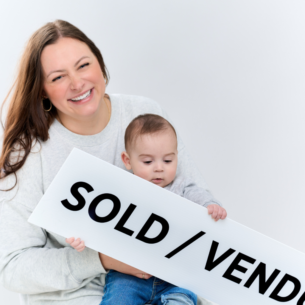Jenny and her son Jackson holding a SOLD sign
